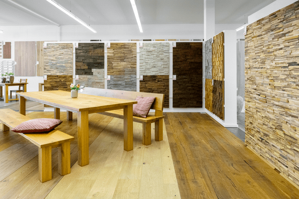 Neben getäfelten Wänden aus Spaltholz steht ein sehr langer Holztisch mit lange Bänken