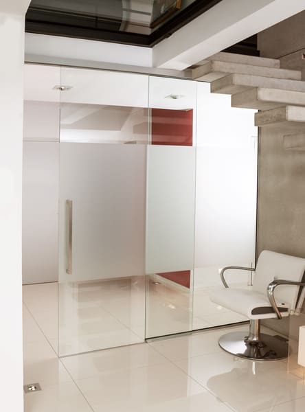 Elegante Glastür in weißem Beton mit roter Wand als Kontrast
