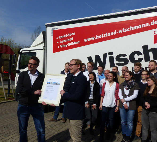 Jubiläumsbild mit den Mitarbeitern von HolzLand Wischmann vor einem LKW