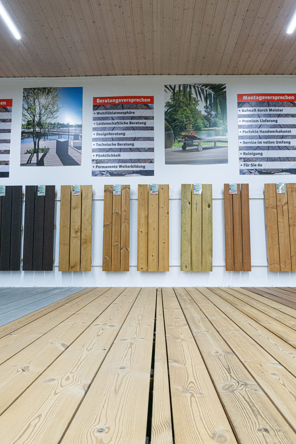 Ausstellung Holzterrassen: Eine Große Auswahl an Holzterrassendielen, die auf dem Boden und an der Wand montiert sind