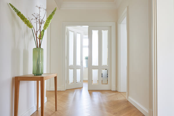 Ein minimalistisch eingeräumter Gang führt zu einer eleganten Doppeltür mit eingelassenen Glasscheiben, Denkmalschutz- & Villentüren rundum Witten