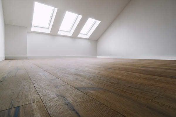 Referenz Parkettboden: in einem leeren, großen Zimmer mit weißen Wänden wurde ein eleganter Parkettboden verlegt