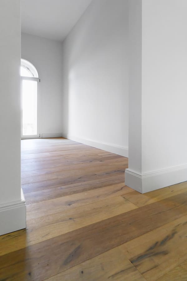Referenz Parkettboden: in einem leeren Gang mit weißen Wänden wurde ein eleganter Parkettboden verlegt